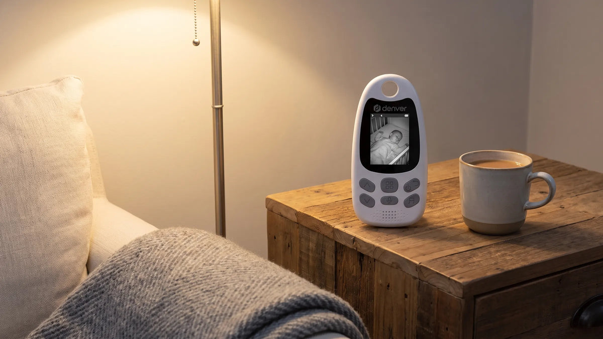 Ouderunit van de Denver BC250 babyfoon met nachtbeeld van een slapende baby op een bijzettafel