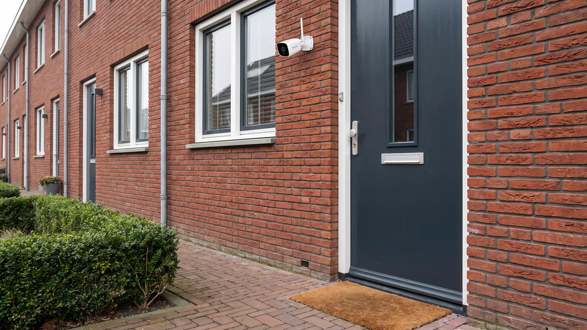 Witte Denver IOC241 beveiligingscamera naast de voordeur van een bakstenen rijtjeshuis