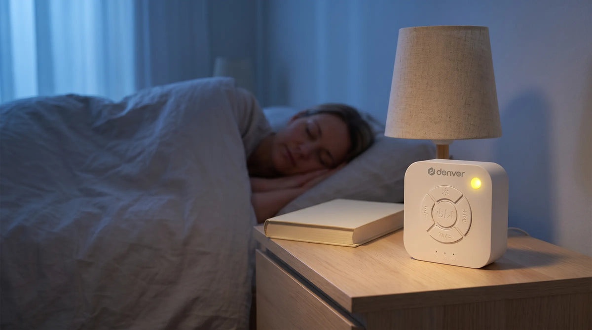 Denver WN93 white noise machine met zacht geel nachtlampje op een nachtkastje terwijl iemand slaapt