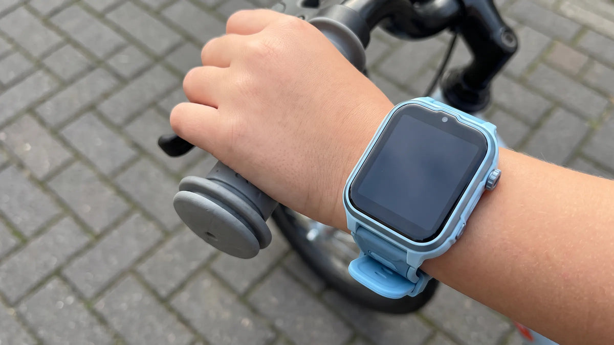 Kinderpols met de lichtblauwe Denver SWGL149 smartwatch op het stuur van een kinderfiets